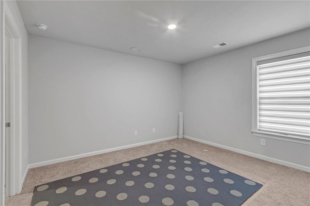 empty room featuring carpet, visible vents, and baseboards