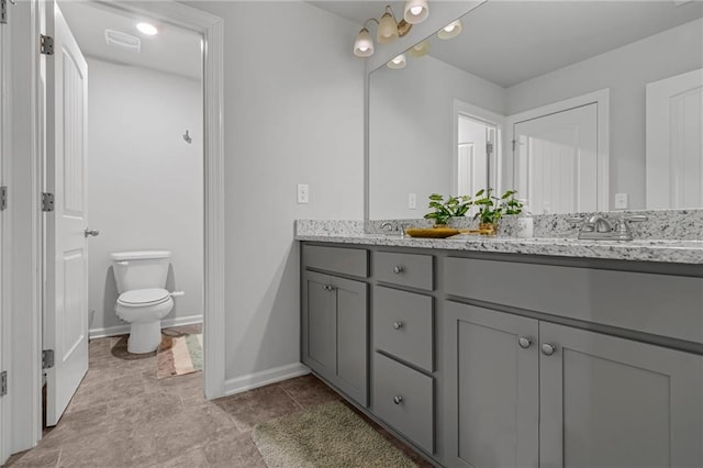 full bath featuring double vanity, baseboards, visible vents, toilet, and a sink