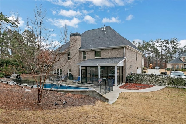 back of house featuring a sunroom, a patio area, fence, and a chimney