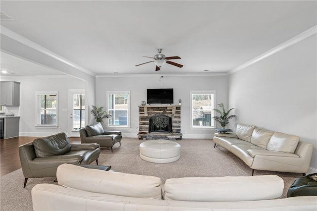 living area featuring a ceiling fan, crown molding, a fireplace, and baseboards