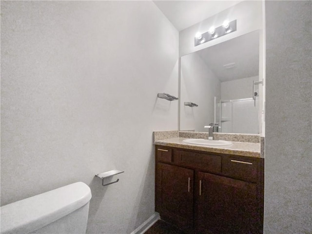 bathroom with vanity, toilet, and a shower with door