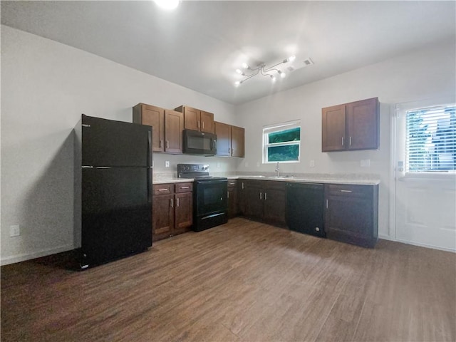 kitchen featuring sink, a wealth of natural light, black appliances, and dark hardwood / wood-style floors