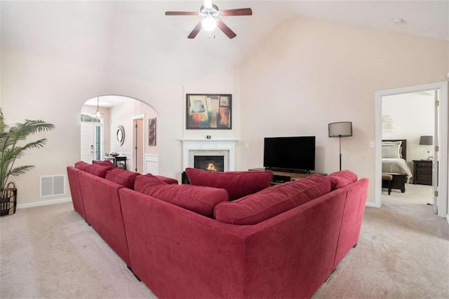 1856 Temple Park Dr, Loganville, GA 30052 - living room with light colored carpet, arched walkways, a ceiling fan, high vaulted ceiling, and a warm lit fireplace