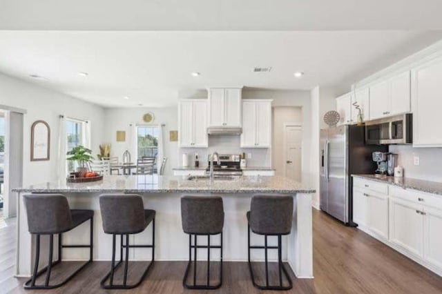 kitchen featuring sink, a breakfast bar area, white cabinetry, stainless steel appliances, and a center island with sink