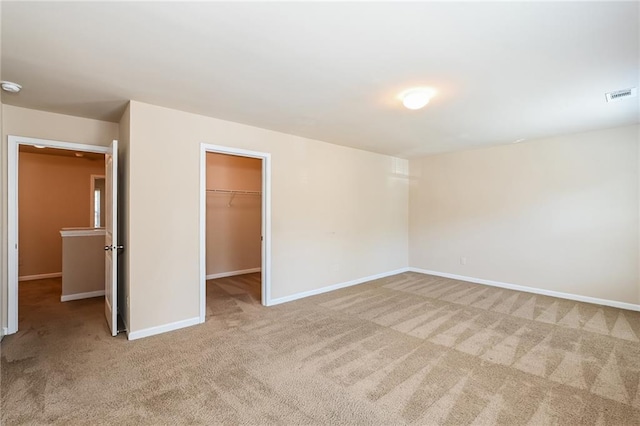 unfurnished bedroom with a walk in closet, a closet, and carpet floors