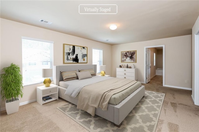 bedroom with ensuite bathroom and light colored carpet