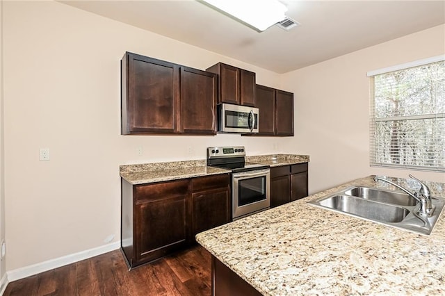 kitchen featuring appliances with stainless steel finishes, dark hardwood / wood-style floors, dark brown cabinets, and sink