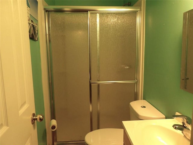 bathroom with vanity, toilet, and a shower with door