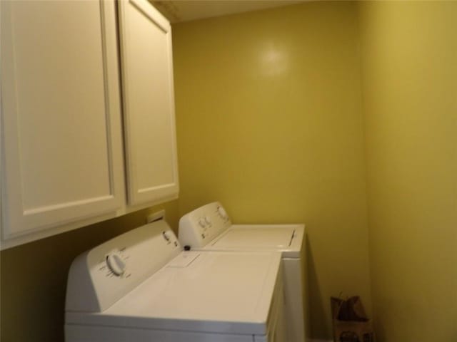 clothes washing area with cabinets and washing machine and dryer