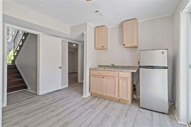 kitchen with sink, light hardwood / wood-style floors, white fridge, ornamental molding, and light brown cabinets