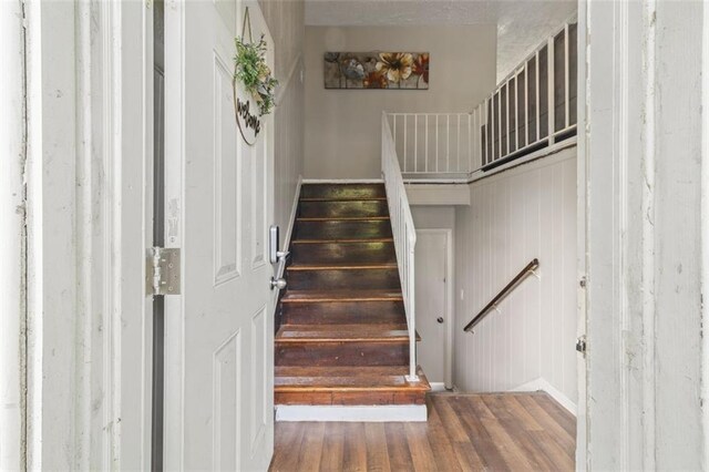 staircase with wooden walls and hardwood / wood-style floors