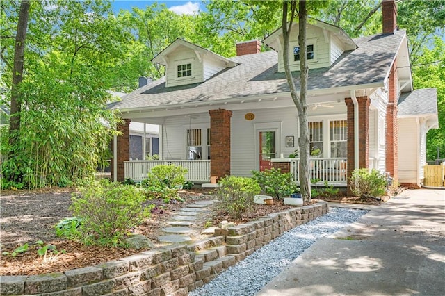 cape cod-style house with a chimney, a porch, and brick siding