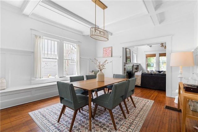 dining room with coffered ceiling, beamed ceiling, hardwood / wood-style floors, a wainscoted wall, and a chandelier