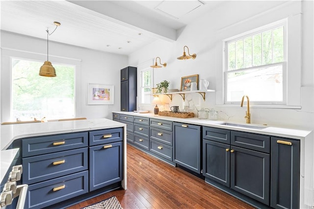kitchen featuring a sink, dark wood-type flooring, pendant lighting, blue cabinetry, and beamed ceiling