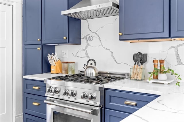 kitchen with wall chimney range hood, high end range, blue cabinetry, and light stone countertops
