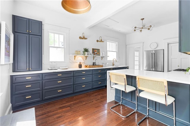 kitchen with high end fridge, dark wood-type flooring, light countertops, a kitchen bar, and open shelves