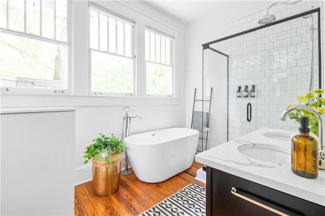 bathroom with a shower stall, wood finished floors, vanity, and a soaking tub