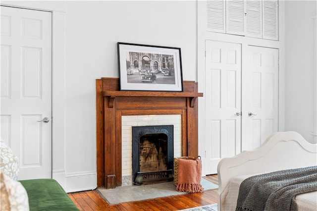 bedroom with wood finished floors, a brick fireplace, and baseboards