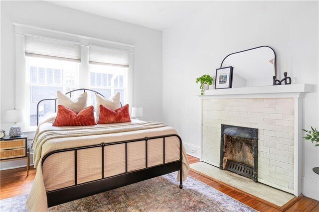 bedroom featuring a brick fireplace and wood finished floors