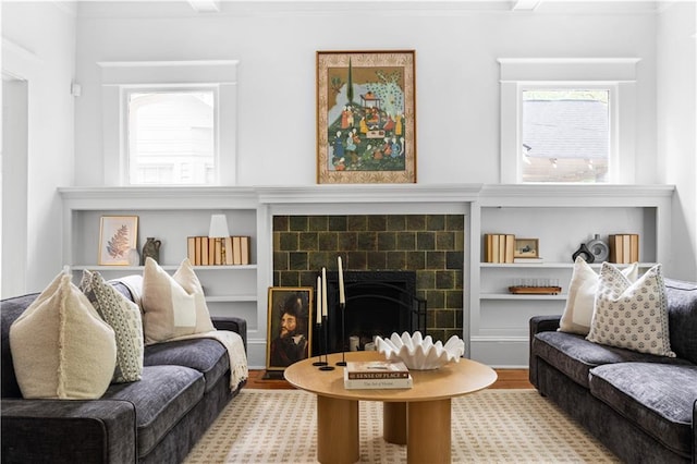 living room featuring crown molding, wood finished floors, a fireplace, and built in features