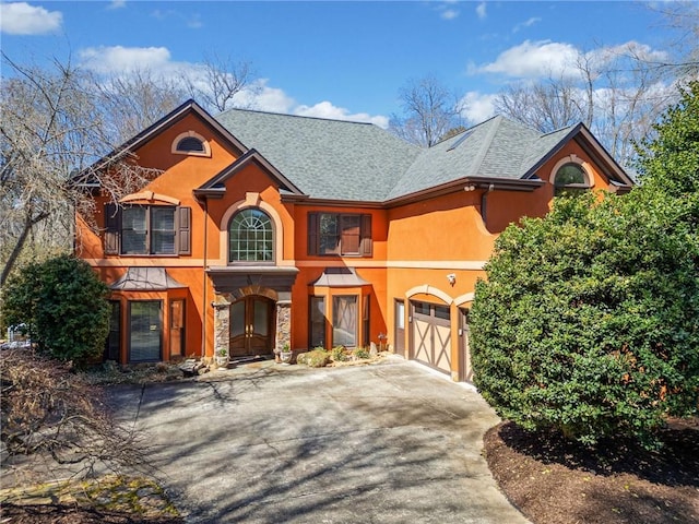 view of front facade with an attached garage, stone siding, driveway, and stucco siding