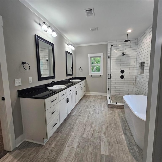6093 Wayarer Dr, Villa Rica, GA 30180 - bathroom featuring a stall shower, a soaking tub, double vanity, baseboards, and wood finished floors