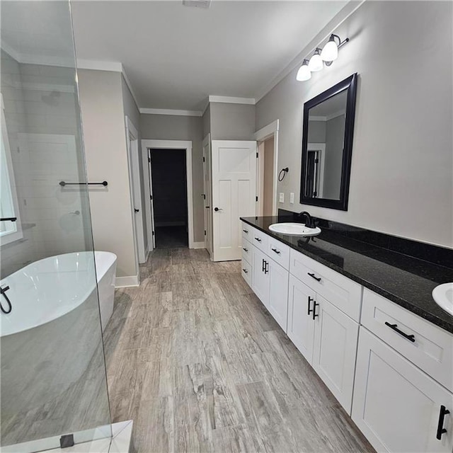 6093 Wayarer Dr, Villa Rica, GA 30180 - full bathroom featuring a freestanding bath, double vanity, crown molding, baseboards, and wood finished floors