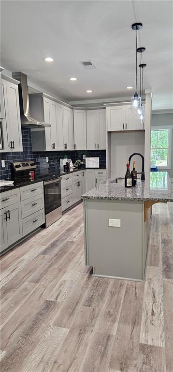 6093 Wayarer Dr, Villa Rica, GA 30180 - kitchen featuring wall chimney range hood, light stone counters, hanging light fixtures, backsplash, and recessed lighting