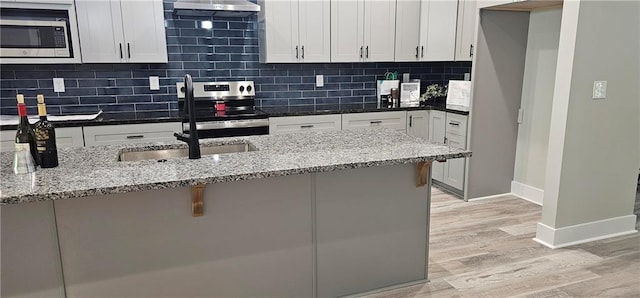 6093 Wayarer Dr, Villa Rica, GA 30180 - kitchen with stainless steel appliances, baseboards, light wood-type flooring, a sink, and backsplash