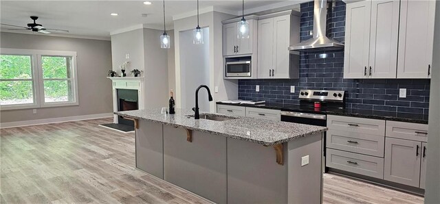 6093 Wayarer Dr, Villa Rica, GA 30180 - kitchen featuring wall chimney range hood, appliances with stainless steel finishes, a sink, ceiling fan, and a kitchen bar