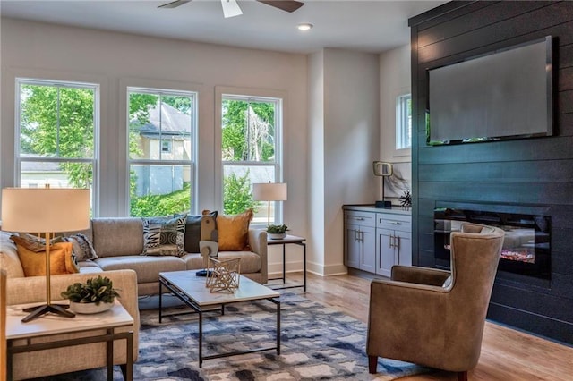 living area featuring light hardwood / wood-style floors, a large fireplace, and ceiling fan