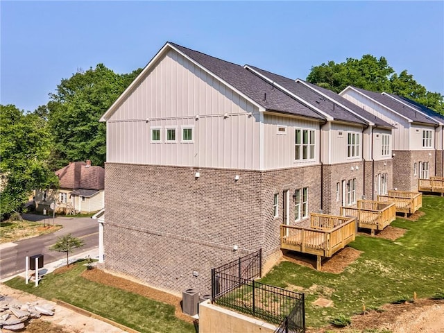 back of house featuring a deck, a lawn, and cooling unit