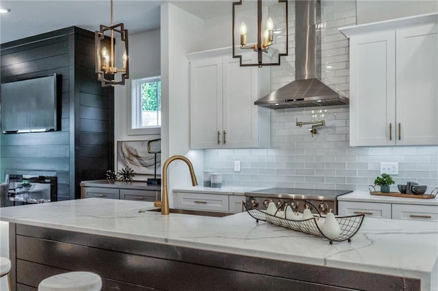 kitchen with wall chimney exhaust hood, white cabinetry, and pendant lighting