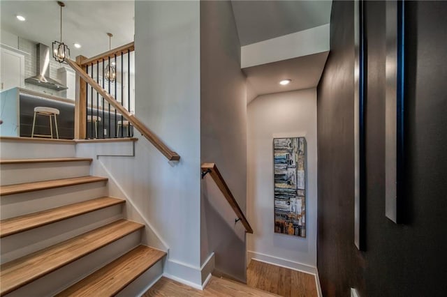 stairs featuring a notable chandelier and wood-type flooring