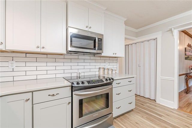 1667 Quail Run, Conyers, GA 30094 - kitchen featuring appliances with stainless steel finishes, light countertops, light wood-style flooring, crown molding, and backsplash