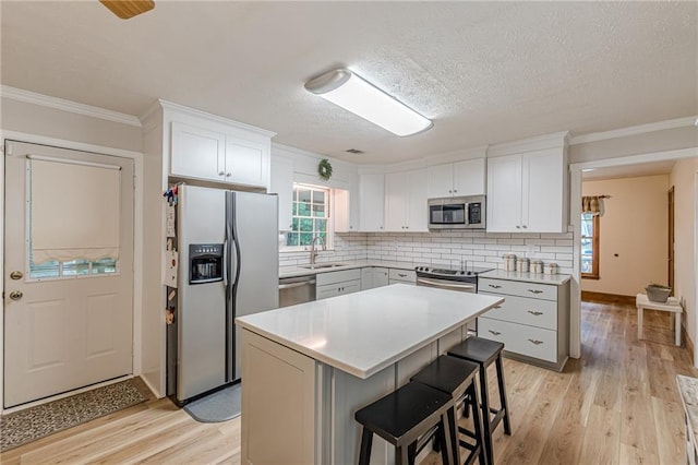 1667 Quail Run, Conyers, GA 30094 - kitchen featuring stainless steel appliances, light wood-style floors, light countertops, a kitchen bar, and decorative backsplash