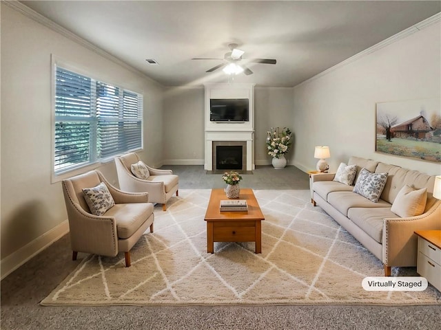 carpeted living room with ceiling fan, baseboards, ornamental molding, and a fireplace