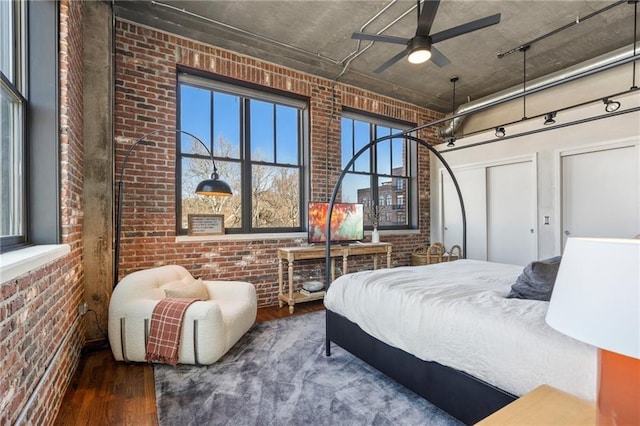 bedroom featuring brick wall, wood-type flooring, and a high ceiling