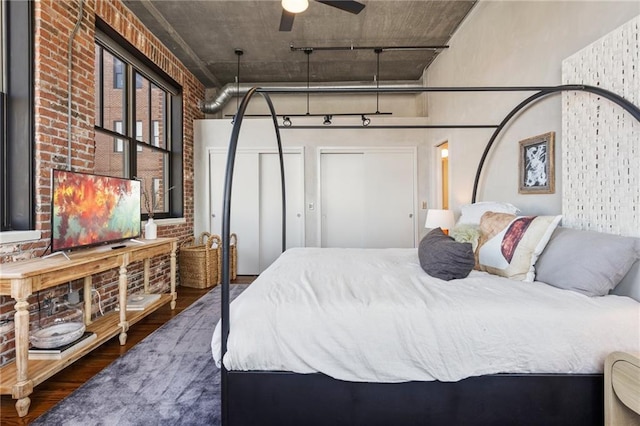 bedroom featuring dark wood-type flooring, brick wall, and a high ceiling