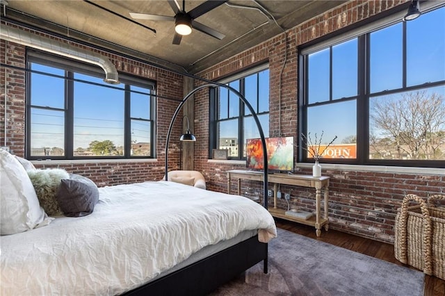 bedroom featuring hardwood / wood-style flooring, a towering ceiling, and brick wall