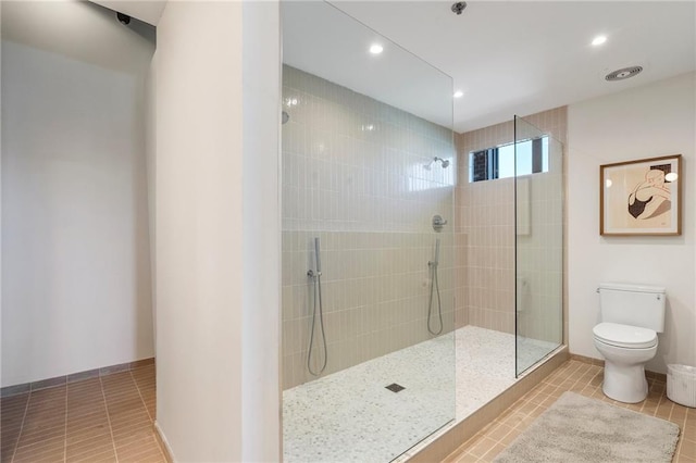 bathroom featuring tile patterned floors, toilet, and a tile shower