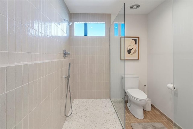 bathroom with tile patterned flooring, toilet, and tiled shower