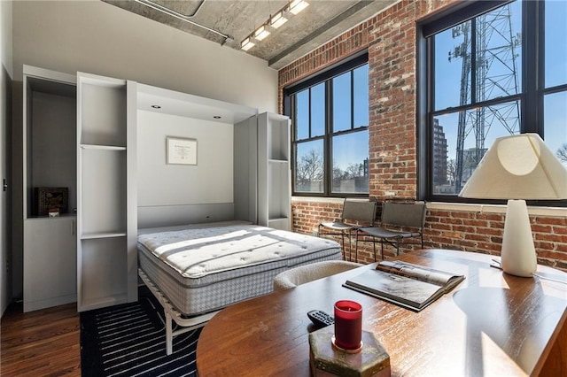 bedroom featuring brick wall and hardwood / wood-style floors