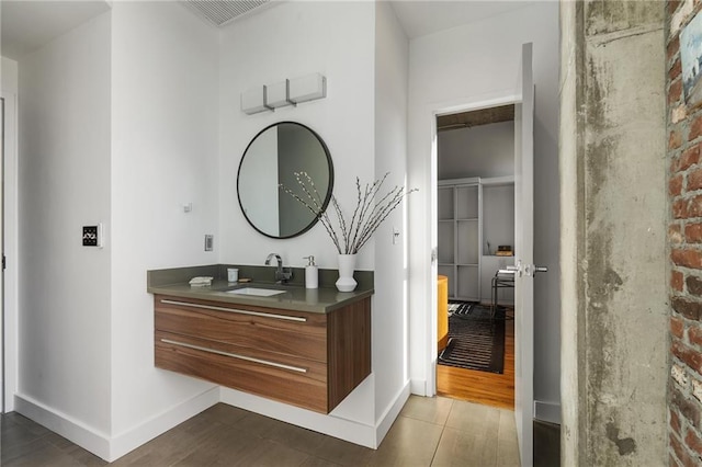 bathroom with vanity and brick wall