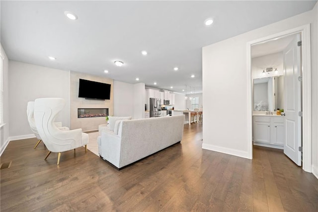 living area featuring dark wood-style floors, recessed lighting, visible vents, a large fireplace, and baseboards