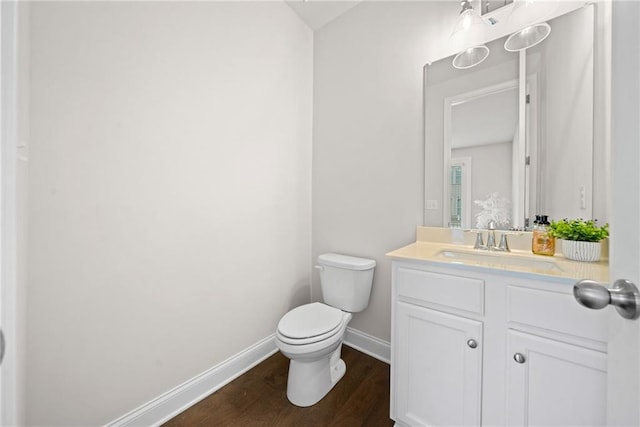 bathroom featuring toilet, baseboards, wood finished floors, and vanity