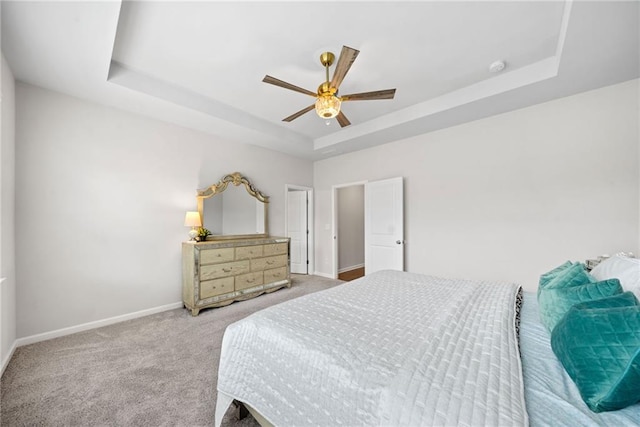 bedroom with carpet, a tray ceiling, ceiling fan, and baseboards