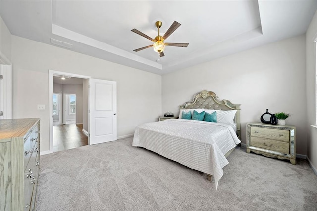 bedroom featuring visible vents, baseboards, a ceiling fan, carpet, and a tray ceiling