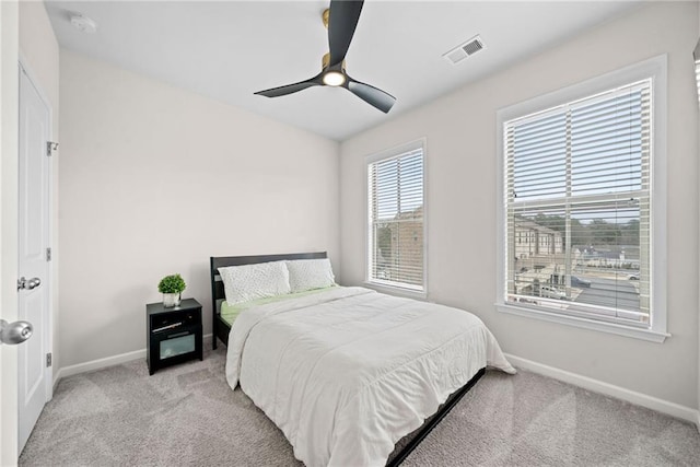 bedroom with light carpet, baseboards, visible vents, and a ceiling fan