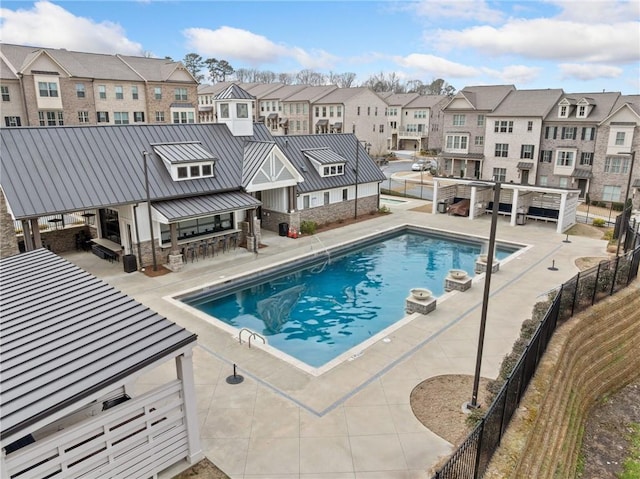 community pool with a residential view, fence, outdoor dry bar, and a patio